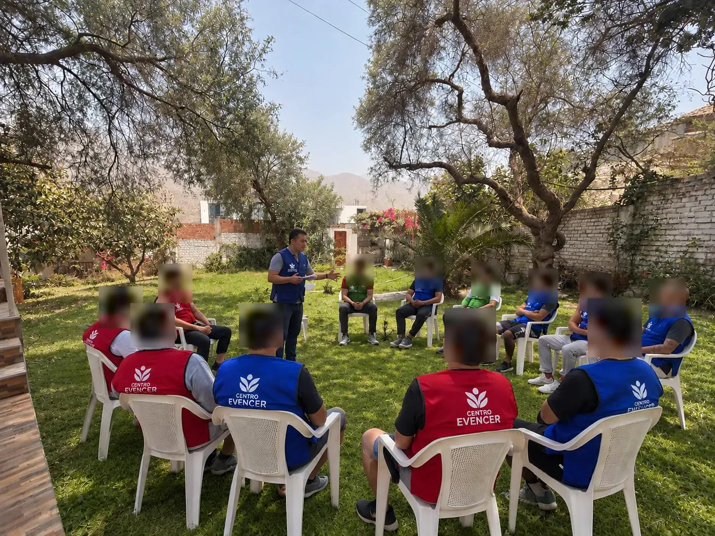 Sesión de terapia de grupo en el jardín, con los pacientes sentados en círculo. Sus rostros están difuminados para proteger su privacidad